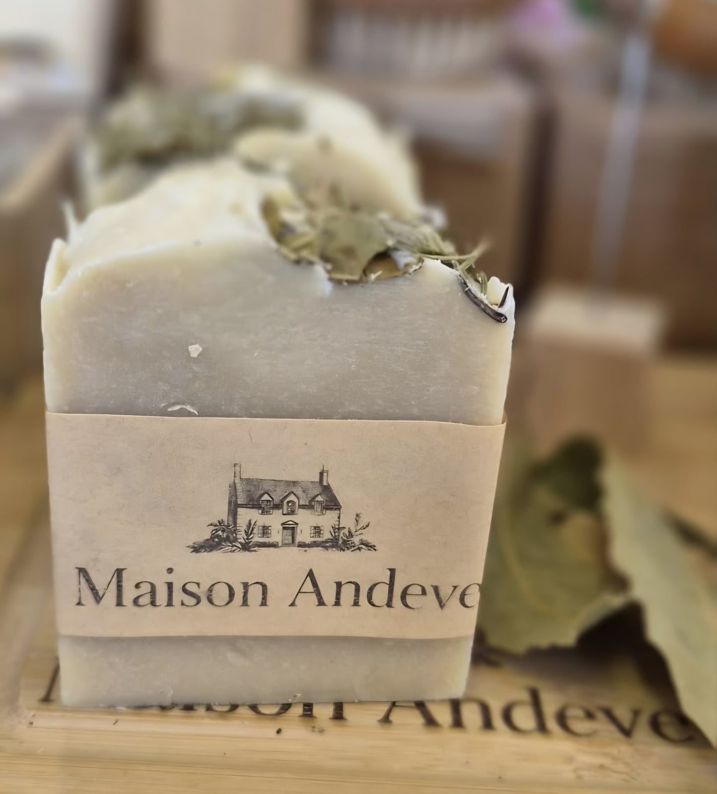 Close up of Maison Andeve botanical soap bar topped with dried leaves, natural handmade skincare product