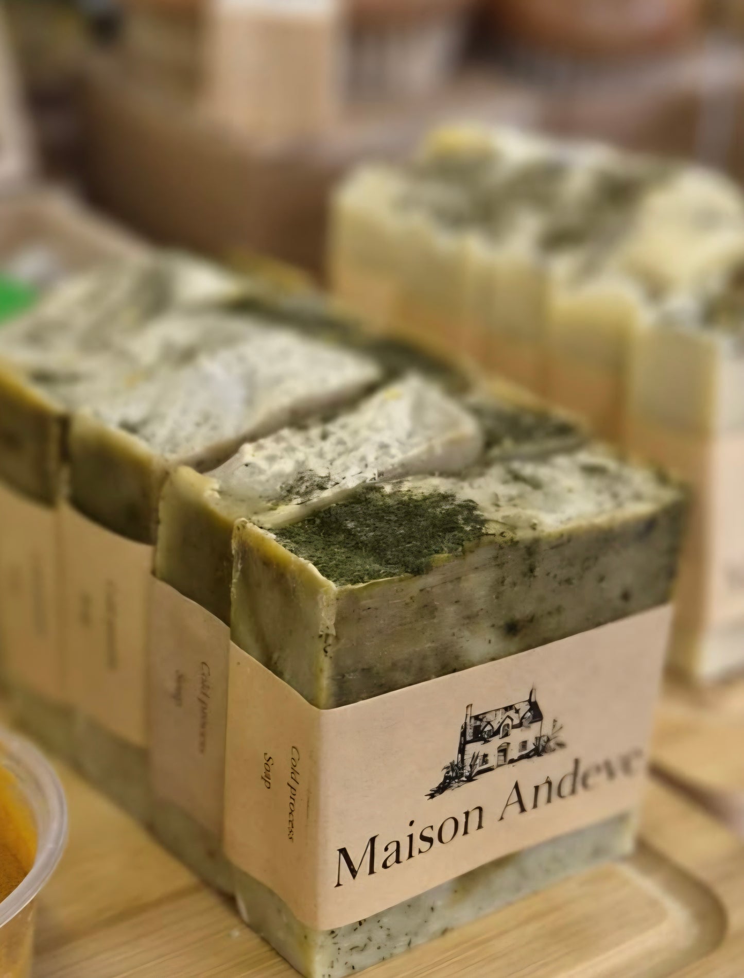Maison Andeve green herbal soap bars stacked with natural textures and botanical ingredients, handmade skincare