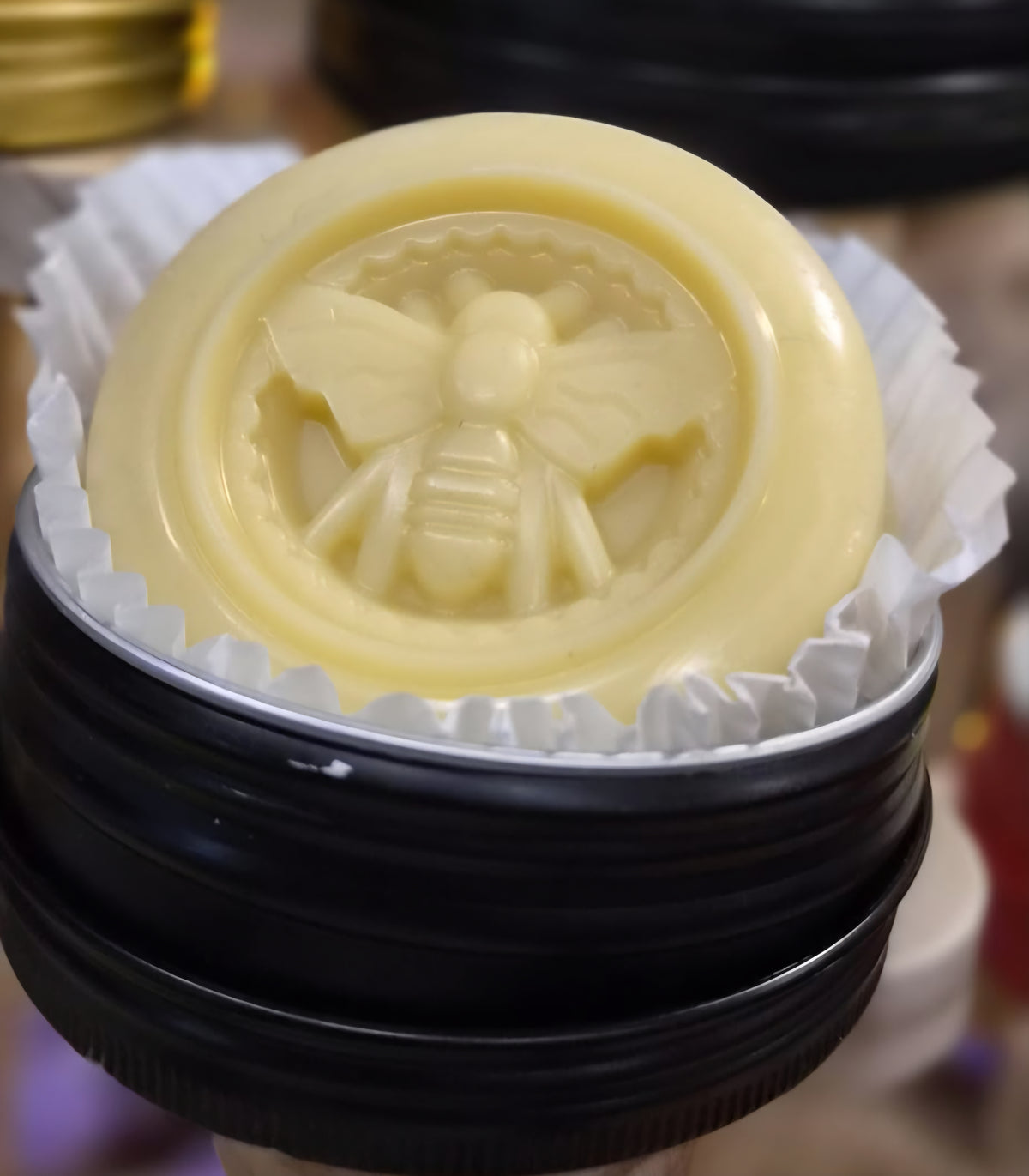 Maison Andeve handmade solid lotion bar with decorative bee design presented in a reusable black tin
