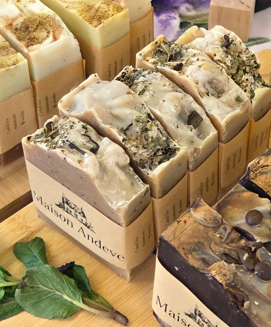 Maison Andeve handmade natural soap bars collection with dried herbs, artisan cold process soaps displayed on wooden tray