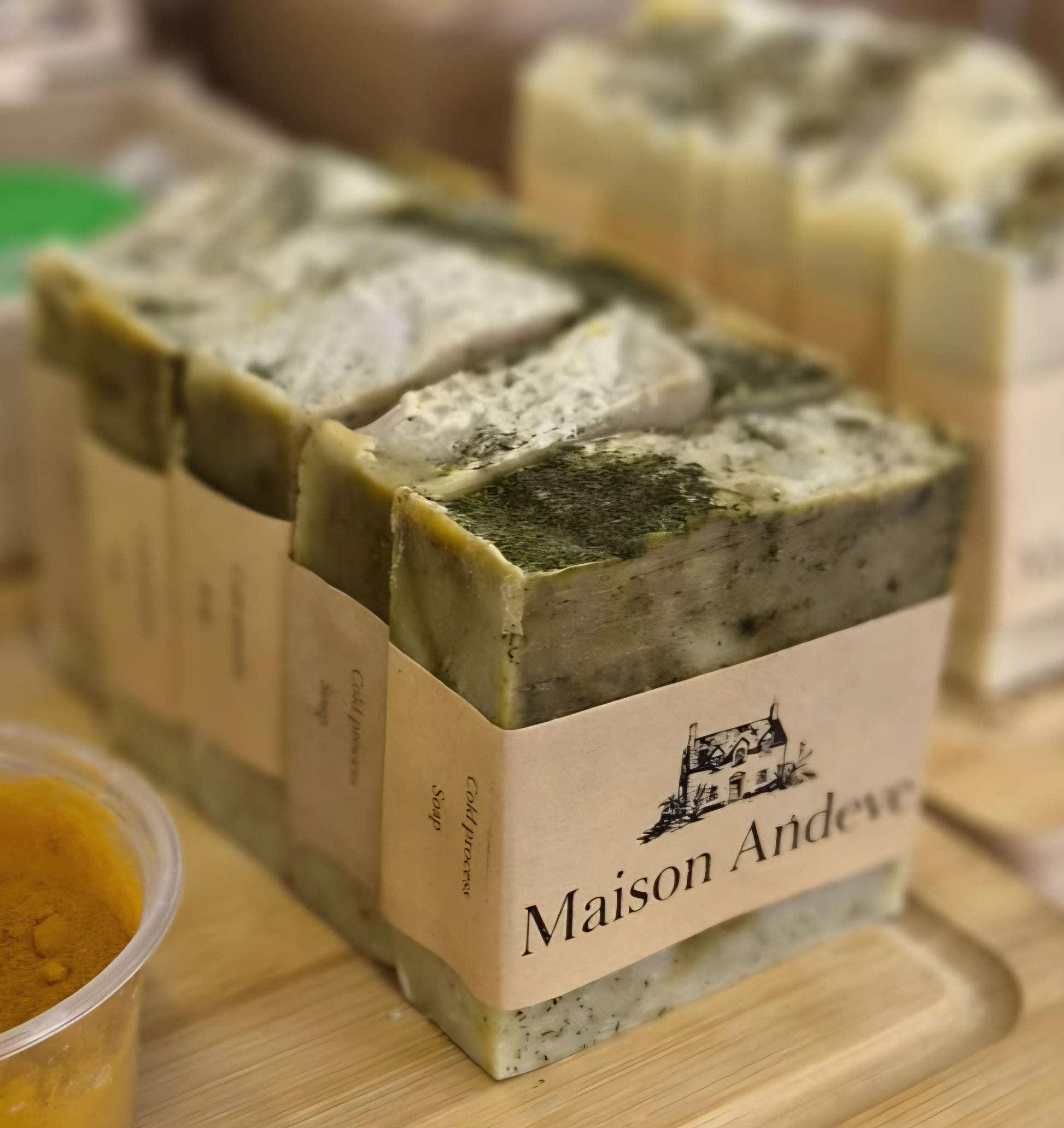 Maison Andeve handmade herbal soap bars arranged together with natural ingredients, artisan cold process skincare collection