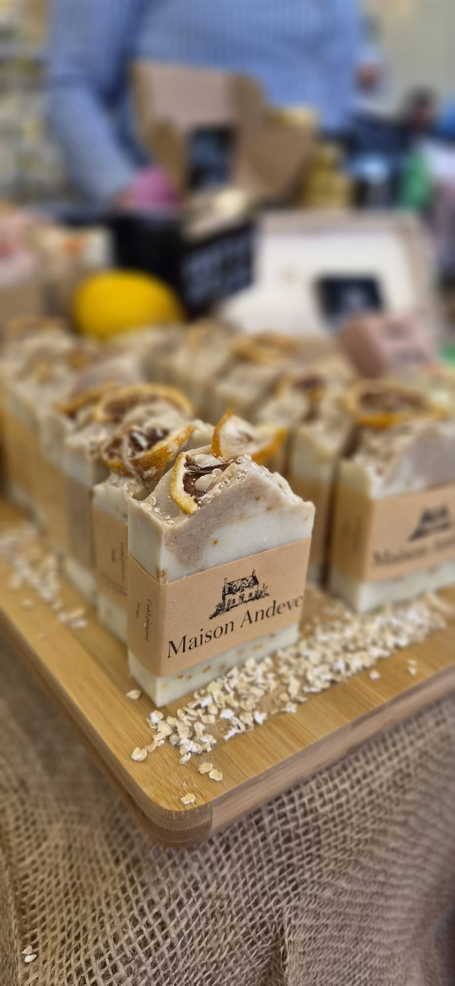 Maison Andeve handmade oat and lemon soap bars displayed at market stall, natural exfoliating skincare with dried citrus